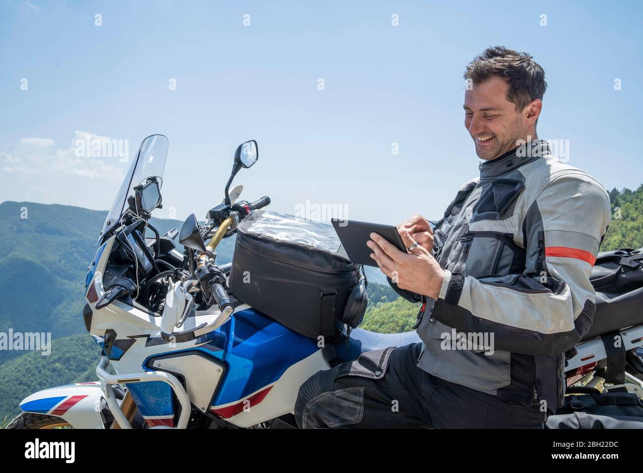 Motorradfahrer auf einer Reise mit einer Pause in den Bergen mit Tablet, Pistoia, Toskana, Italien Stockfoto