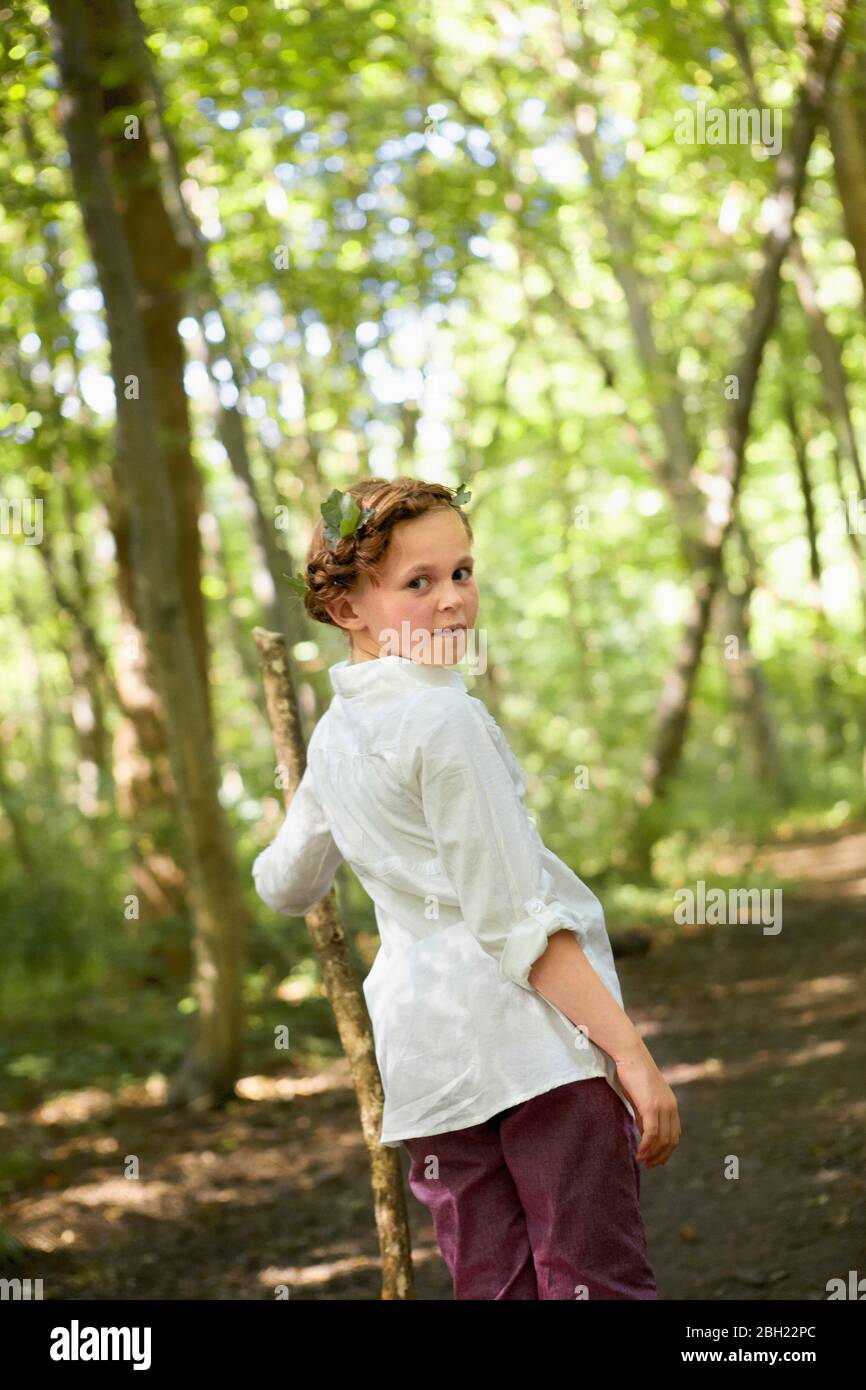 Portrait von Mädchen mit Holzstock zu Fuß im Wald Stockfoto