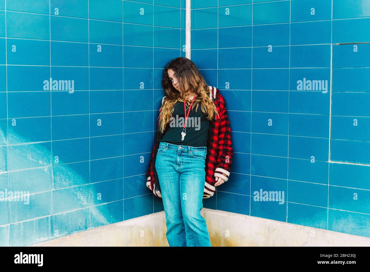 Teenager Mädchen lehnte an gefliesten blauen Wand im Freien Stockfoto