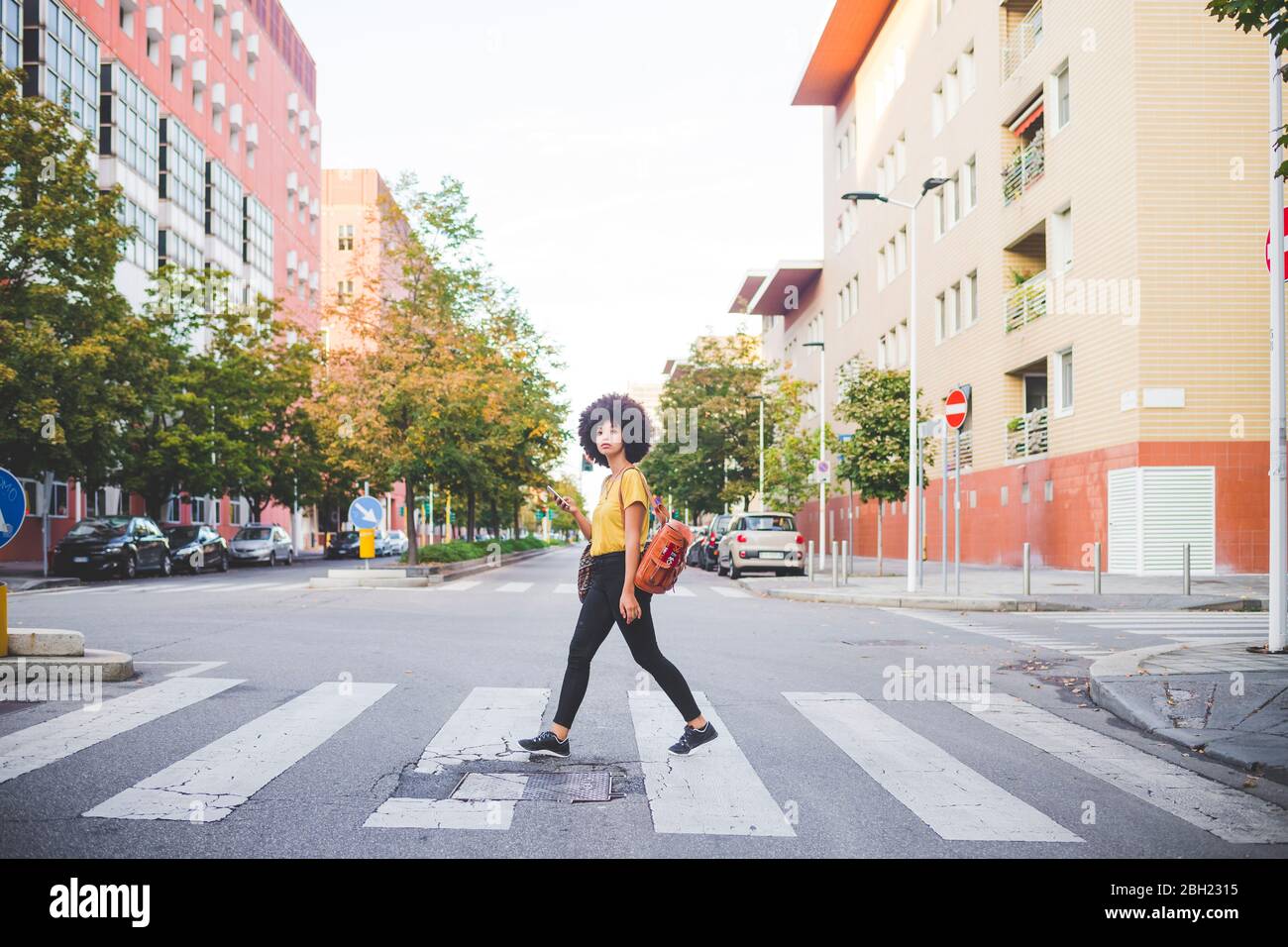 Junge Frau mit Afro-Frisur zu Fuß in der Stadt Stockfoto