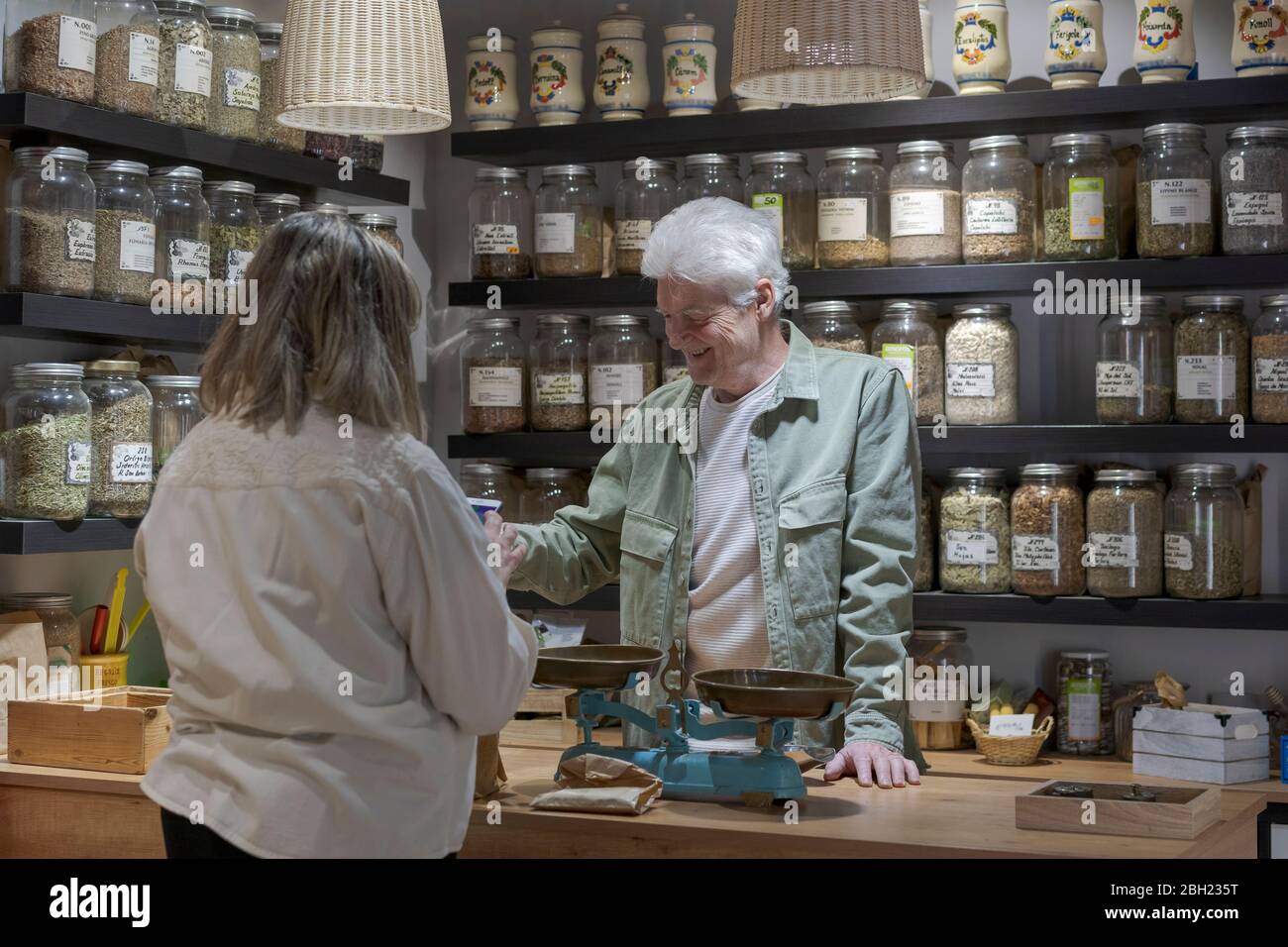 Lächelnder älterer Mann mit dem Kunden hinter dem Tresen in seinem Geschäft Stockfoto