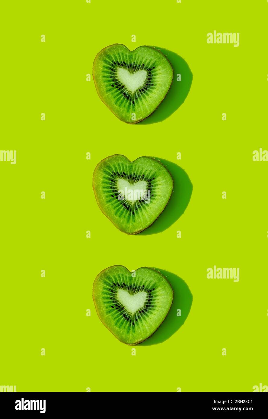 Herzförmige Kiwi-Fruchtscheiben Muster auf grünem Hintergrund Stockfoto