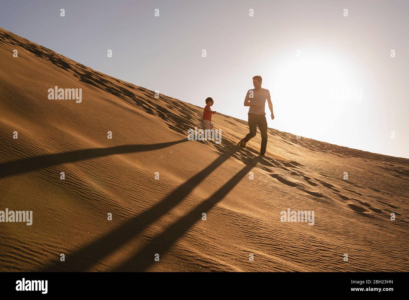 Vater und Tochter laufen bei Sonnenuntergang in Sanddüne, Gran Canaria, Spanien Stockfoto