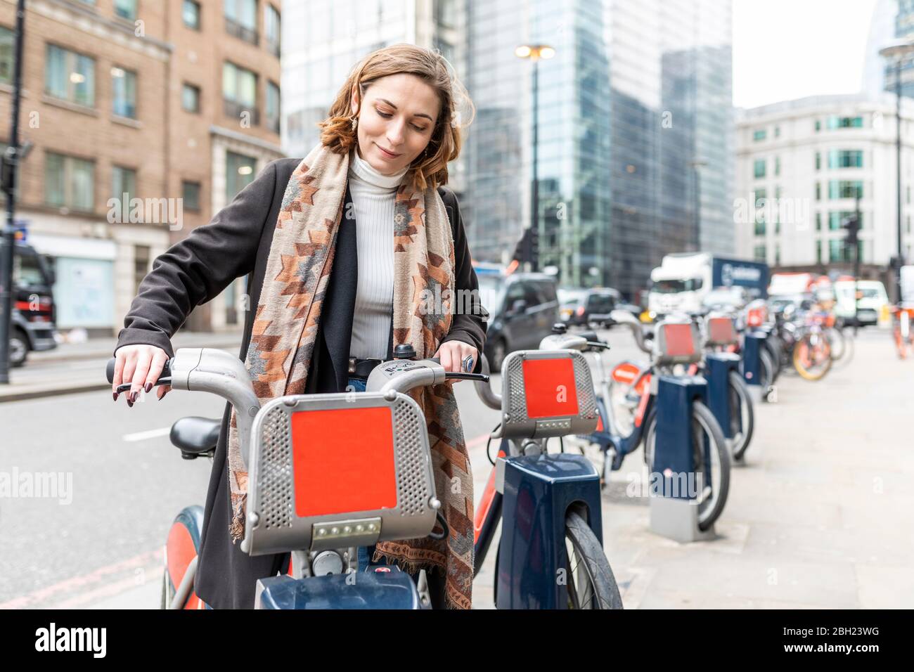 Frau in der Stadt mit Leihrad, London, Großbritannien Stockfoto