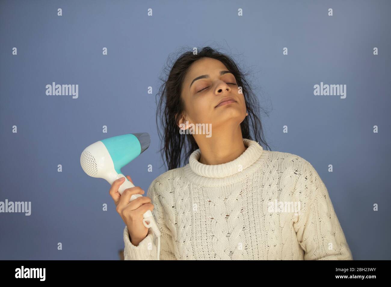 Frau trocknet ihr nasses Haar mit einem Haartrockner. Stockfoto