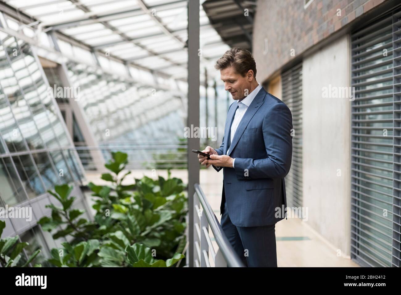 Geschäftsmann mit Smartphone im grünen Atrium Stockfoto