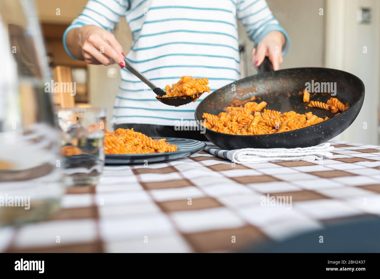 Frau serviert Pasta auf dem Teller zu Hause Stockfoto