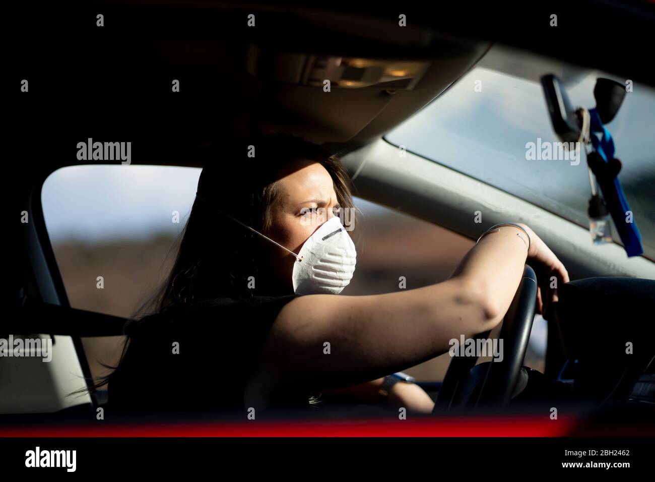 Frau im Auto trägt Atemschutzmaske Stockfoto
