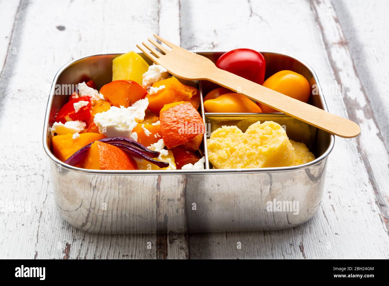 Lunchbox mit herbstlich gebackenem Gemüse, Feta-Käse und herzförmiger Polenta Stockfoto
