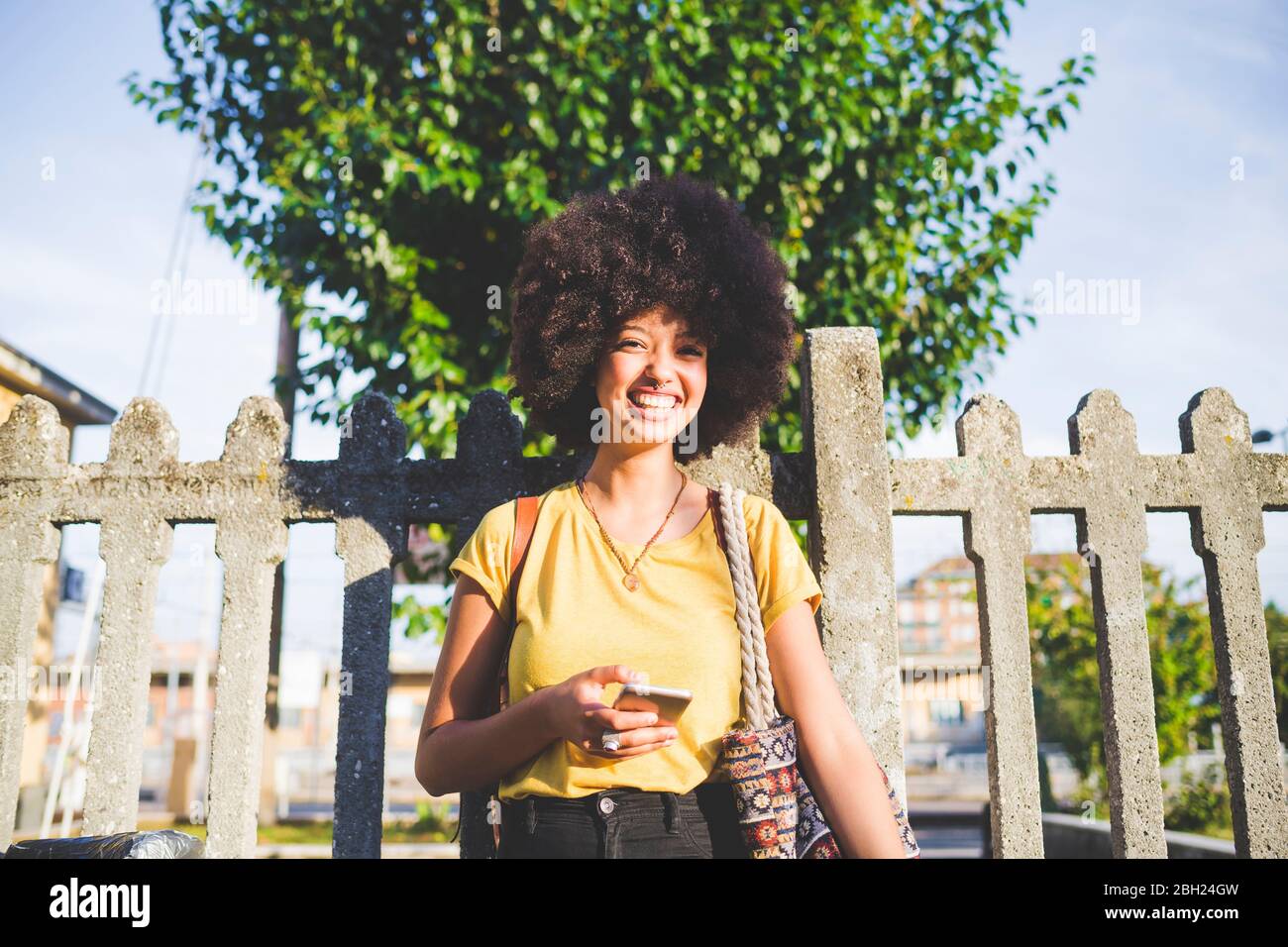Porträt einer glücklichen jungen Frau mit Afro-Frisur in der Stadt Stockfoto