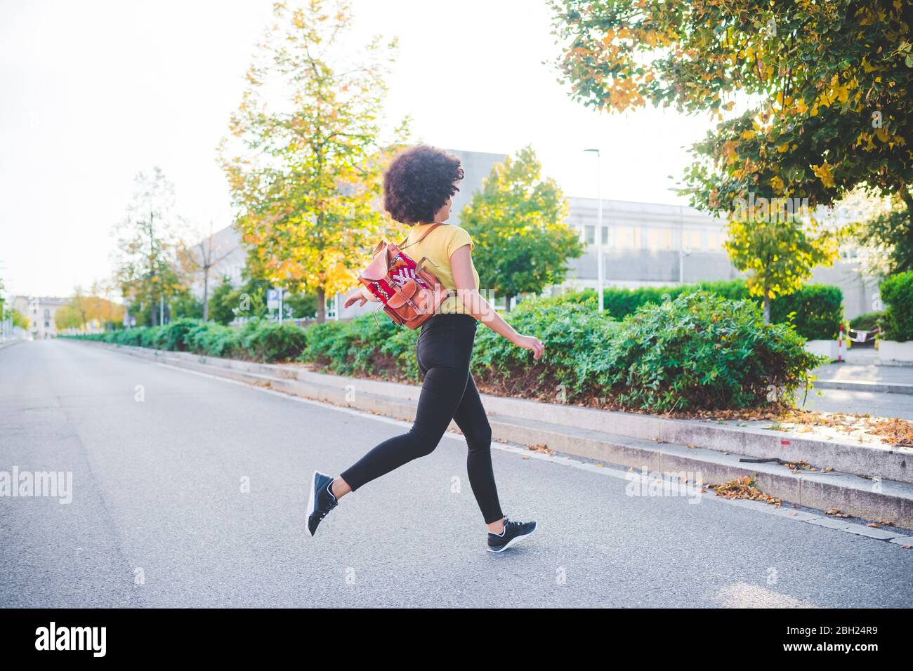 Junge Frau mit Afro-Frisur läuft auf einer Straße in der Stadt Stockfoto