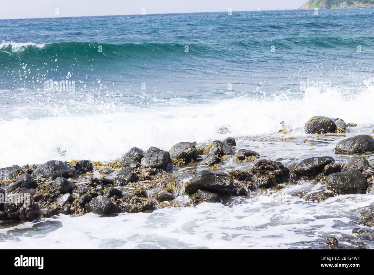 Brechende Welle, die ihren Weg zu einer Felsbarriere macht Stockfoto