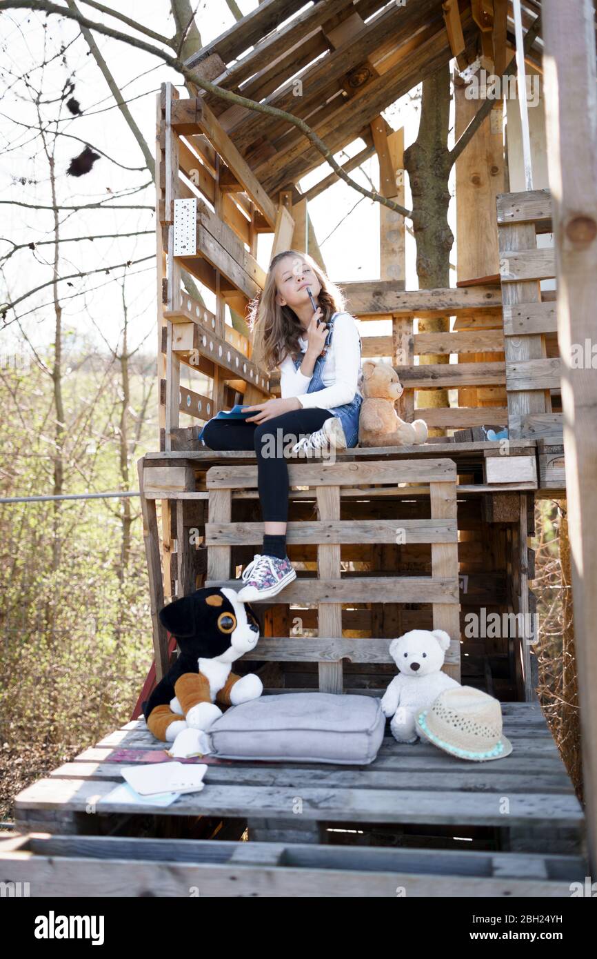 Nachdenkliches Mädchen, das mit ihren Teddybären im Baumhaus spielt Stockfoto