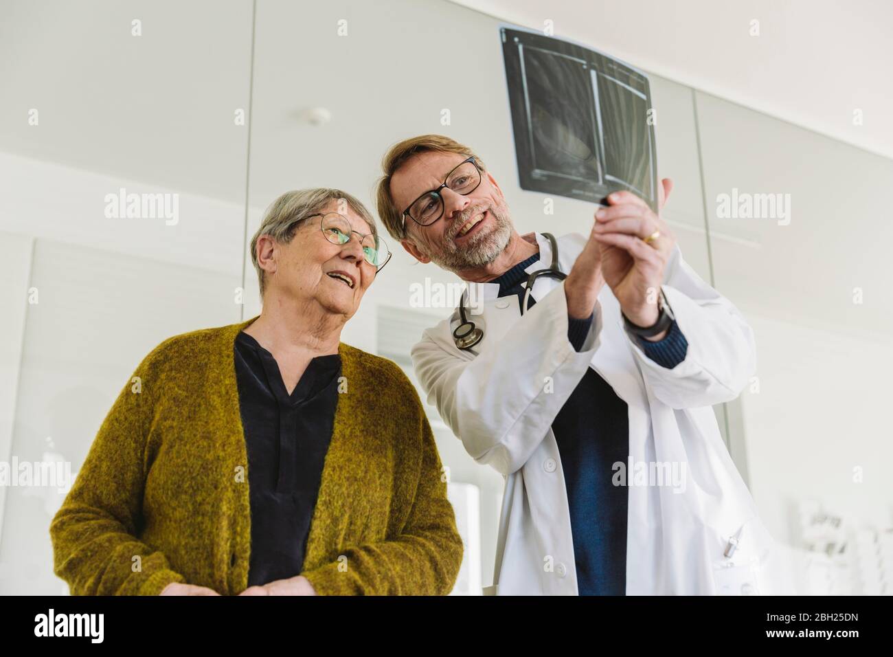 Arzt bespricht Röntgenbild der gebrochenen Hand mit dem älteren Patienten Stockfoto Arzt bespricht Röntgenbild der gebrochenen Hand mit dem älteren Patienten Stockfoto