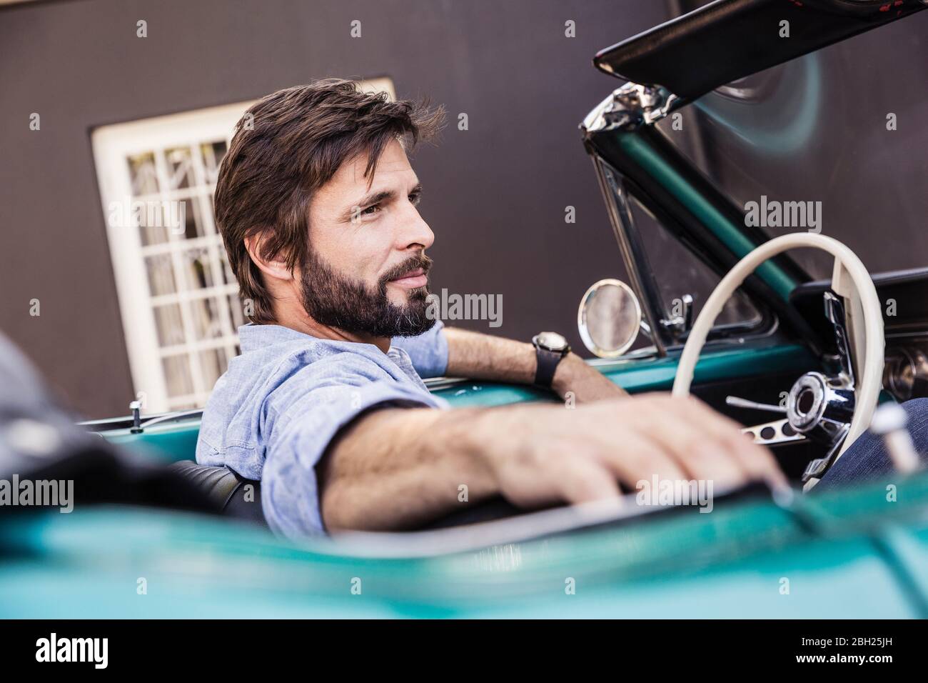 Mann in einem Cabrio vor dem Haus Stockfoto