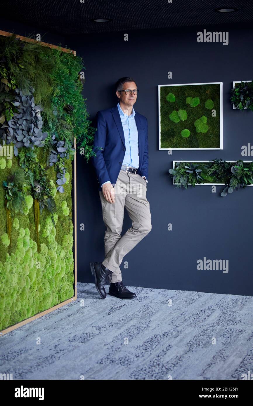 Geschäftsmann steht an der Wand im grünen Büro Stockfoto
