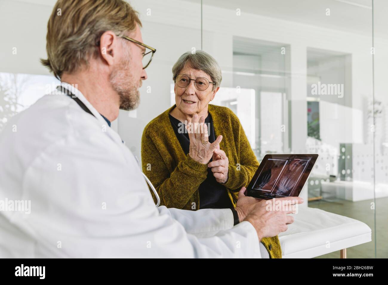 Arzt bespricht Röntgenbild der gebrochenen Hand mit dem älteren Patienten Stockfoto Arzt bespricht Röntgenbild der gebrochenen Hand mit dem älteren Patienten Stockfoto
