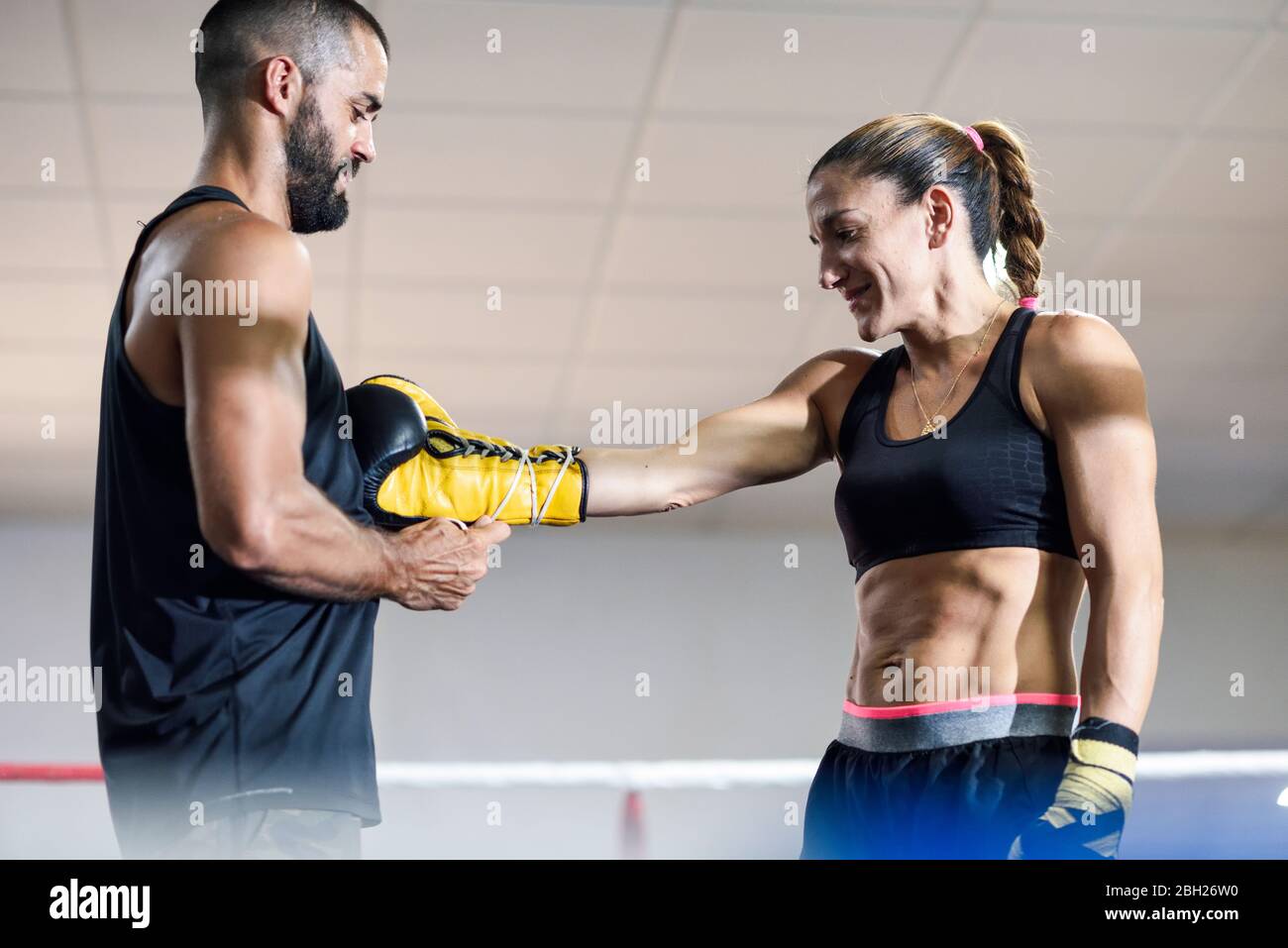 Trainer die Boxhandschuhe auf eine Boxerin legen Stockfoto