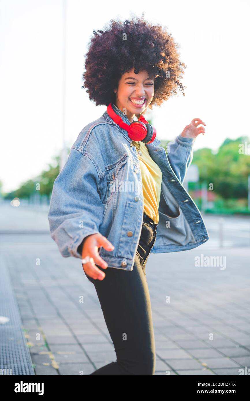 Glückliche junge Frau mit afro Frisur tanzen in der Stadt Stockfoto