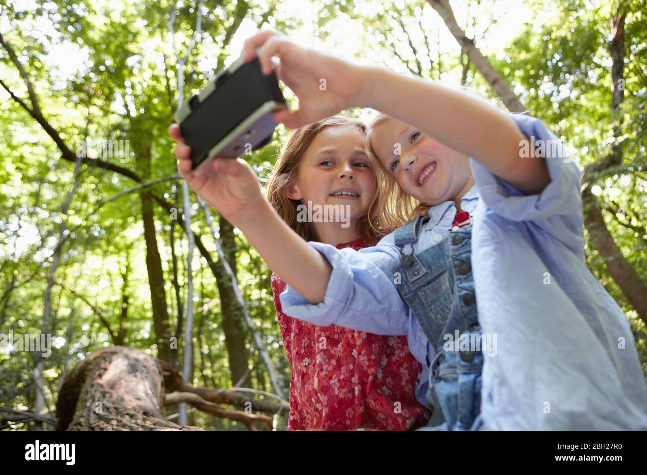Mädchen, die Selfie mit Retro-Kamera im Wald Stockfoto