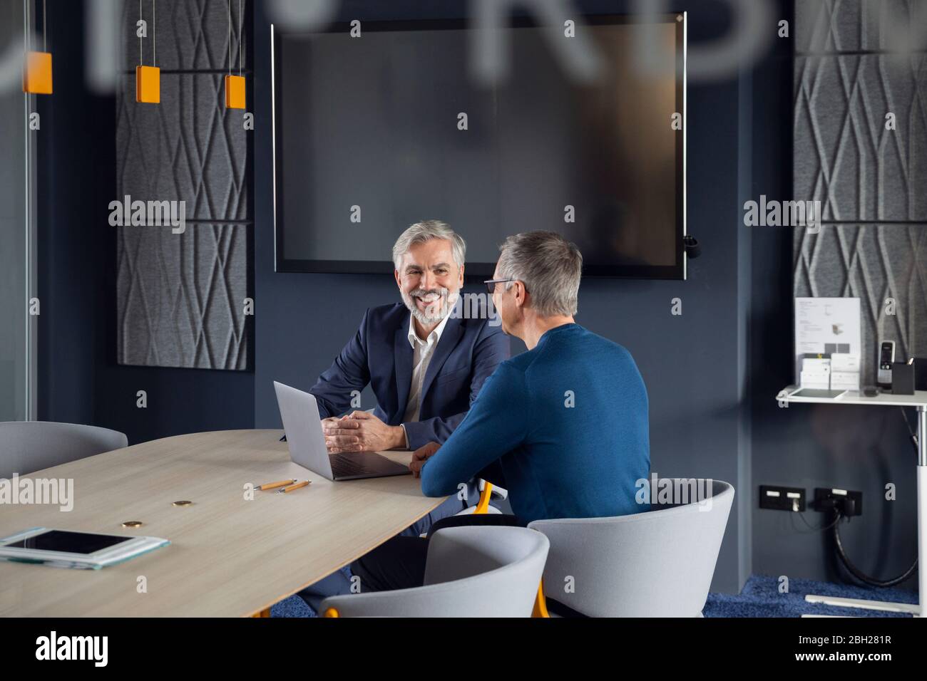 Zwei lächelnde Geschäftsleute, die zusammen an einem Projekt im Büro arbeiten Stockfoto