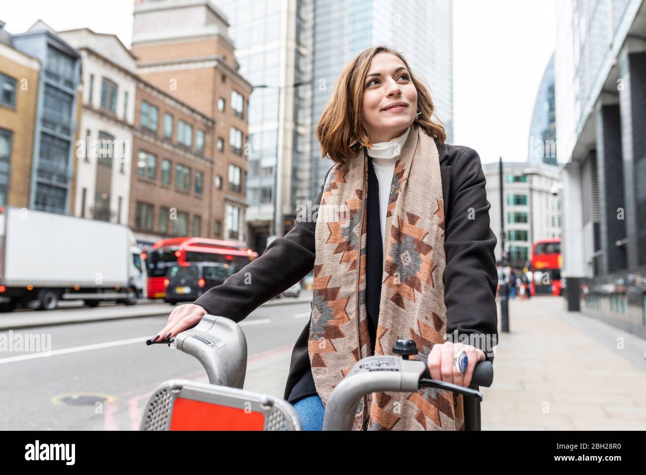 Frau in der Stadt mit Leihrad, London, Großbritannien Stockfoto