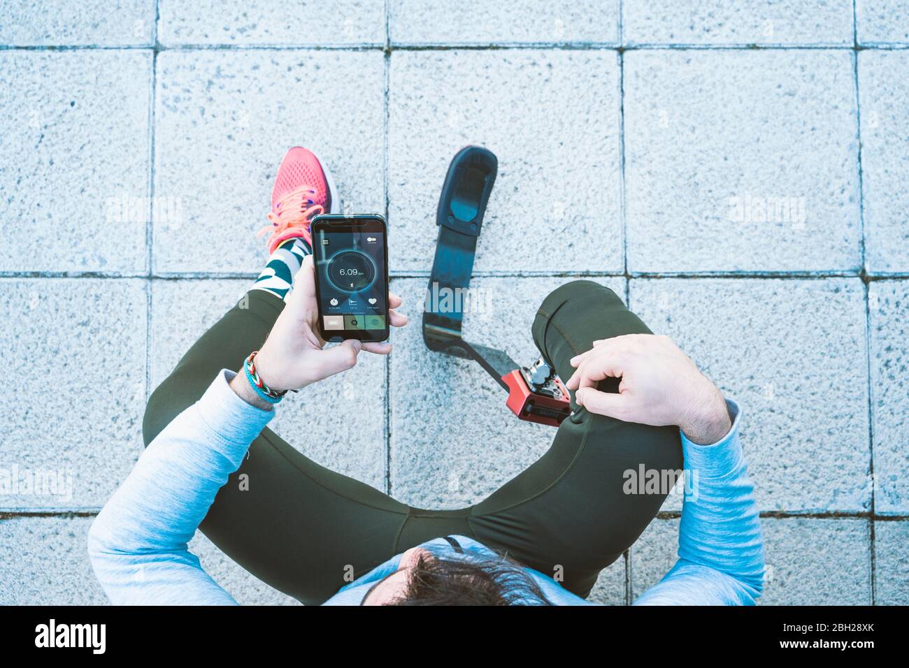 Behinderter Sportler mit Beinprothese eine Pause vom Training machen und Handy mit Daten überprüfen Stockfoto