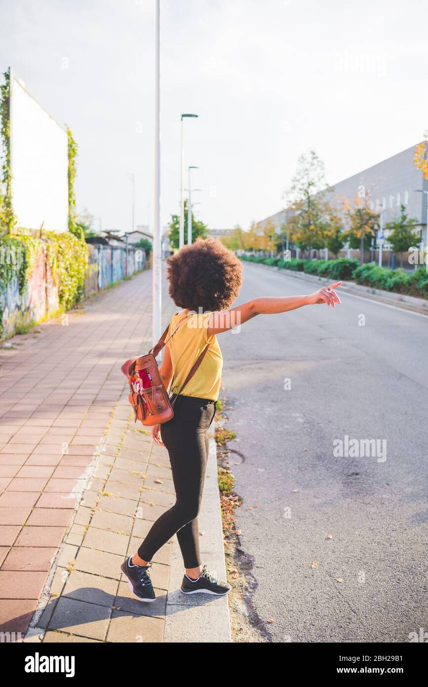 Junge Frau mit afro Hairdo Anhalter in der Stadt Stockfoto