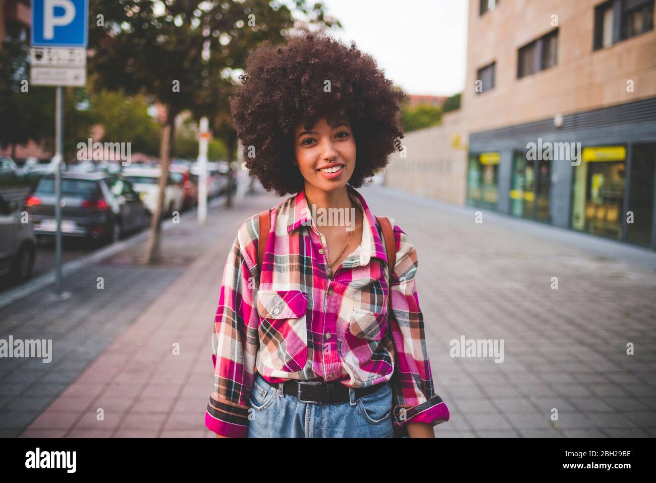 Porträt einer lächelnden jungen Frau mit afro Frisur in der Stadt Stockfoto