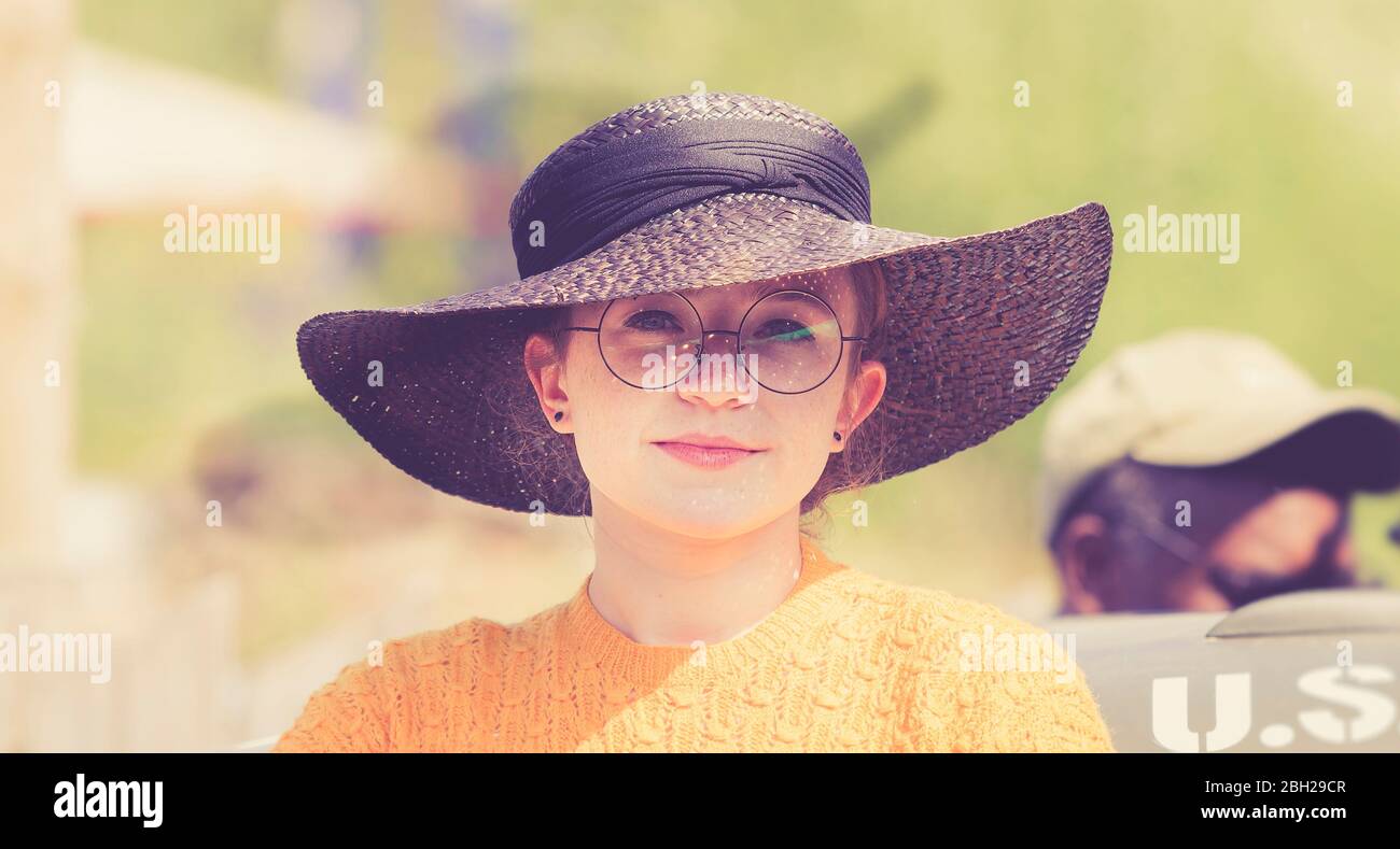 Nahaufnahme des hübschen UK 1940s Mädchens im Sommer Sonnenschein trägt großen Hut, sitzt auf US-Armee-LKW, Black Country Museum Kriegszeit WW2 Veranstaltung. Stockfoto