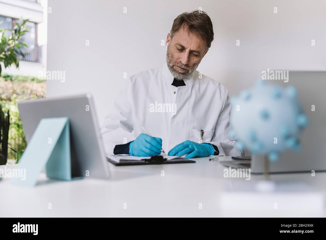 Wissenschaftler, der am Schreibtisch Papiere ausfüllt Stockfoto
