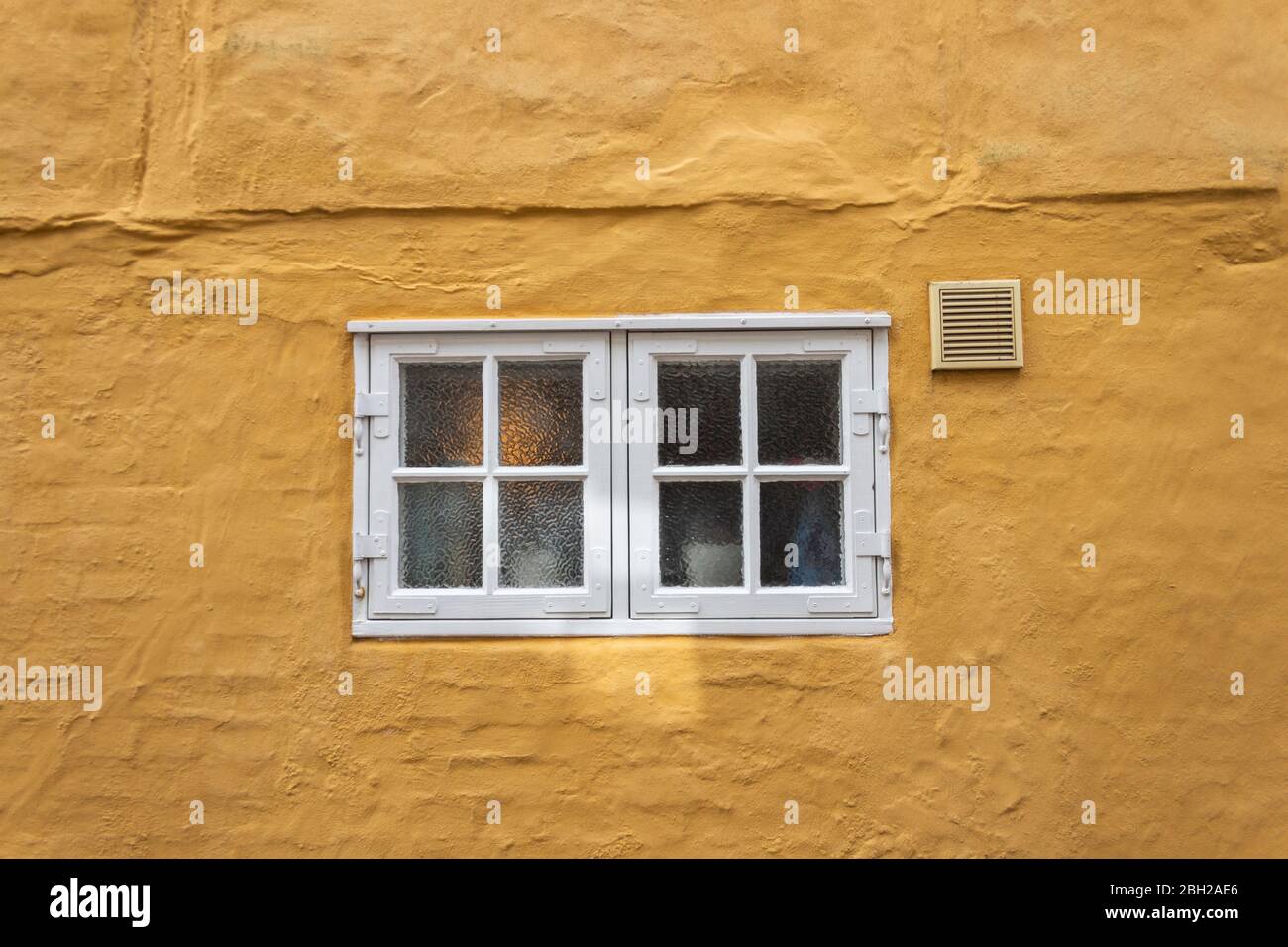 Dänemark, Ribe, kleine Fenster in gelber Hauswand Stockfoto