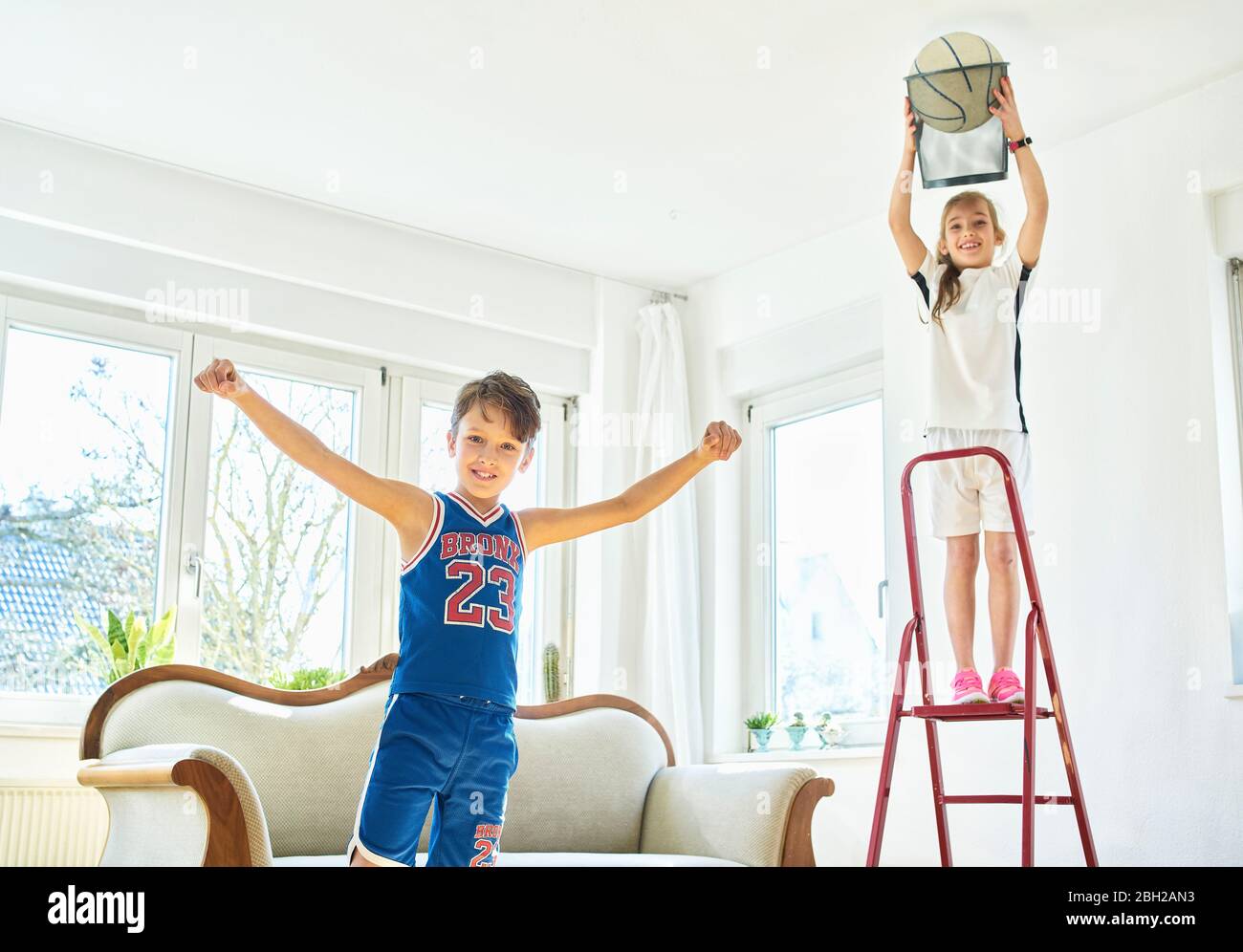Junge und Mädchen spielen Basketball im Wohnzimmer Stockfoto