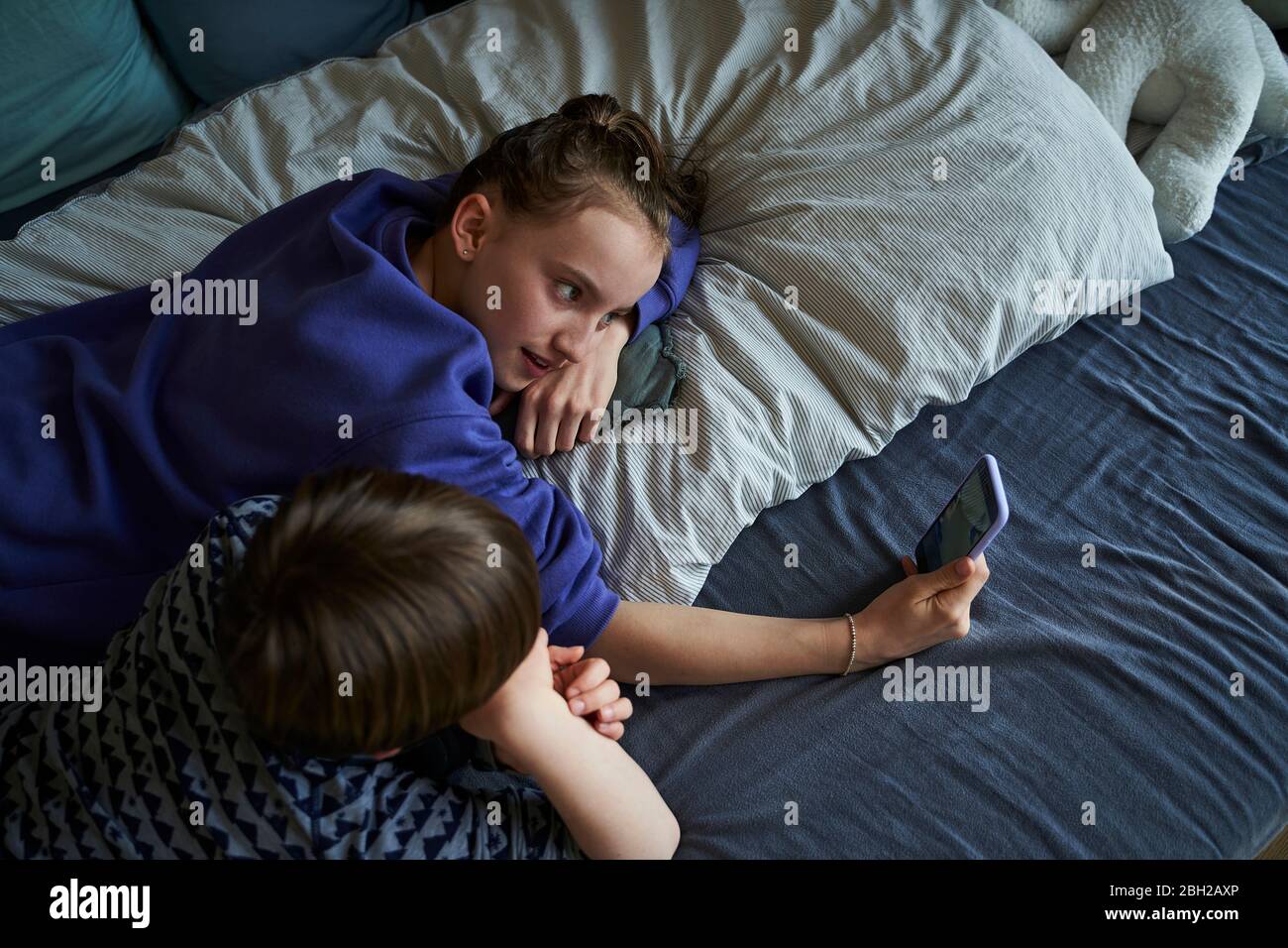 Siblings liegen zusammen auf dem Bett mit Smartphone für Video-Chat Stockfoto