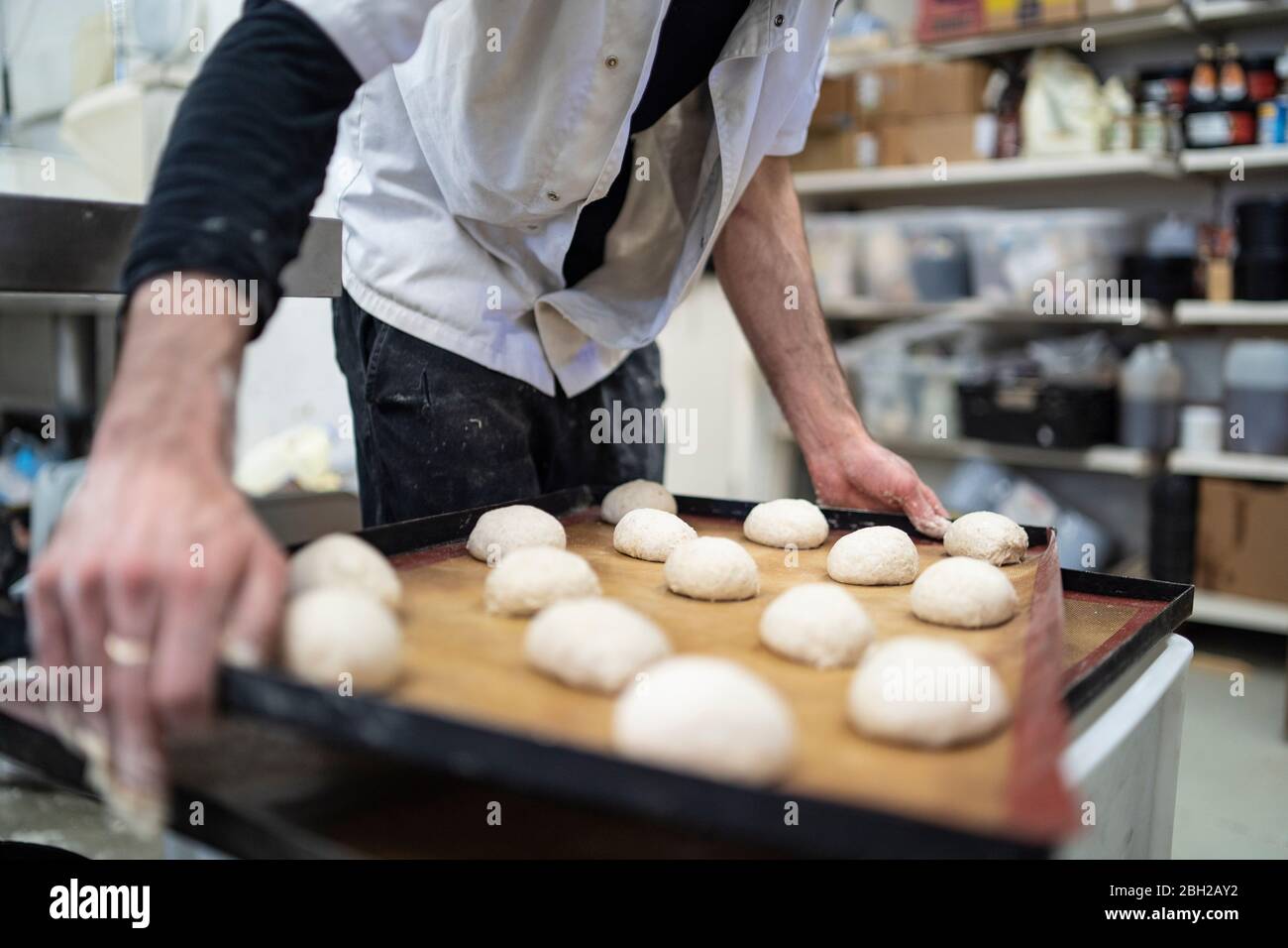 Nahaufnahme des Backers mit Brötchen in der Bäckerei Stockfoto