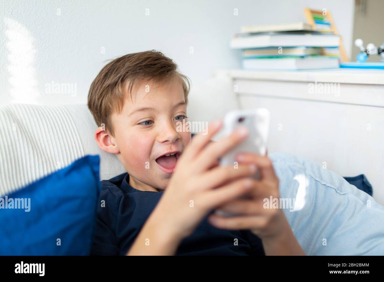 Junge spielt mit seinem Smartphone während der Corona-Krise Stockfoto Junge spielt mit seinem Smartphone während der Corona-Krise Stockfoto