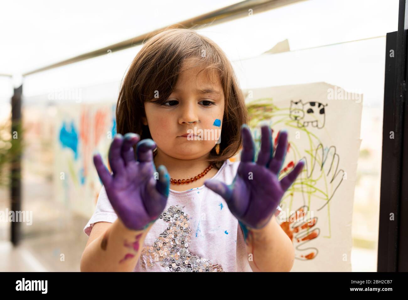 Kleines Mädchen, das mit ihren gemalten Händen herumwirrte Stockfoto