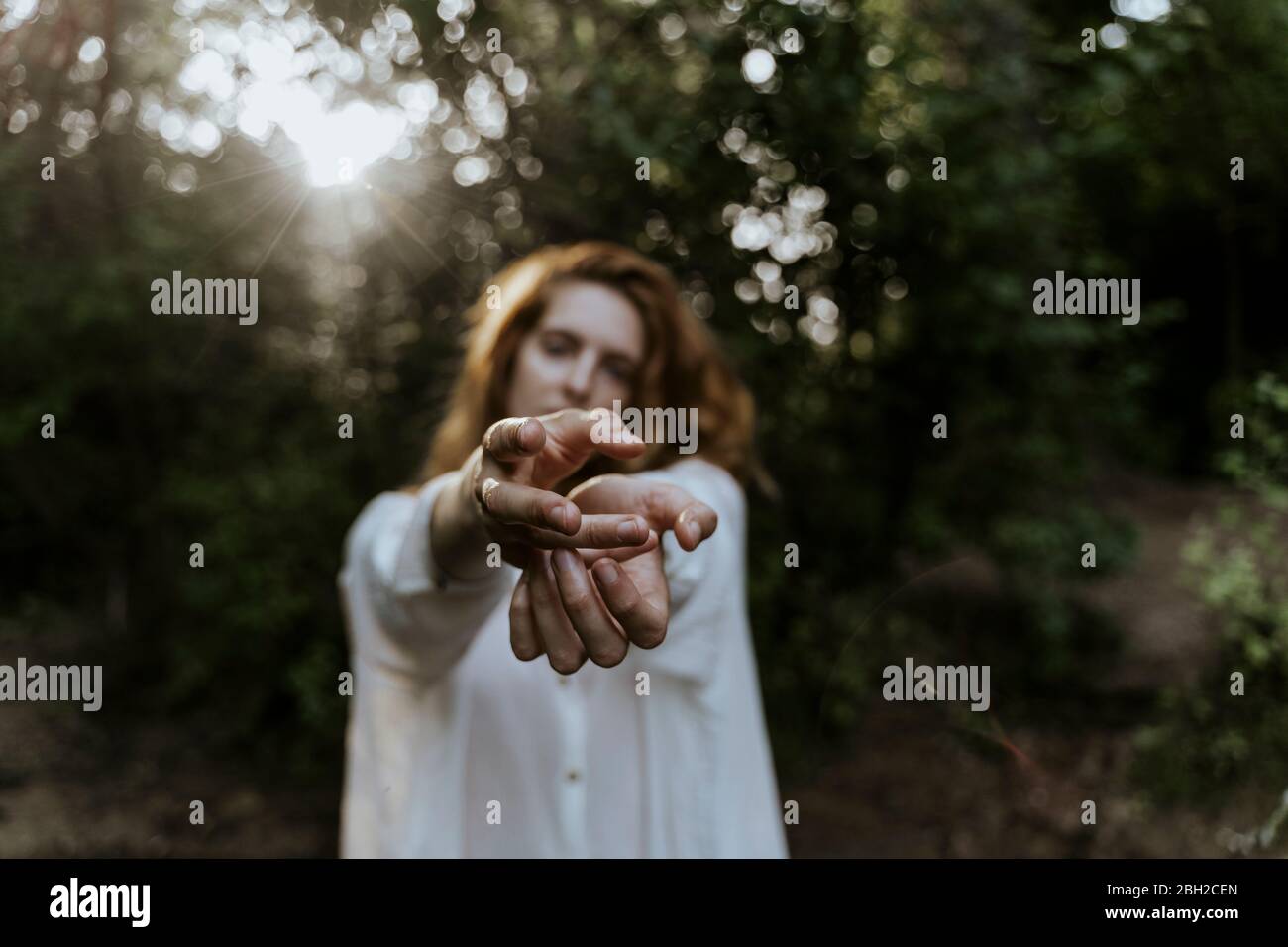 Junge rothaarige Frau streckt ihre Hände im Wald aus Stockfoto