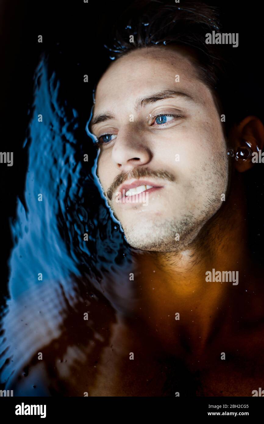 Porträt eines nachdenklichen jungen Mannes mit blauen Augen im Wasser Stockfoto