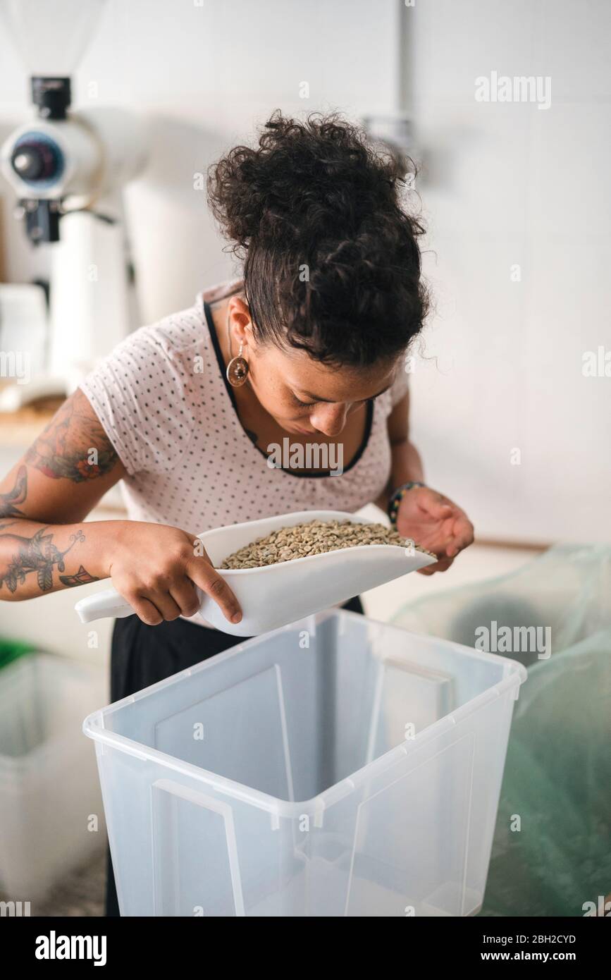 Frau, die in einer Kaffeerösterei arbeitet und Kaffeebohnen untersucht Stockfoto