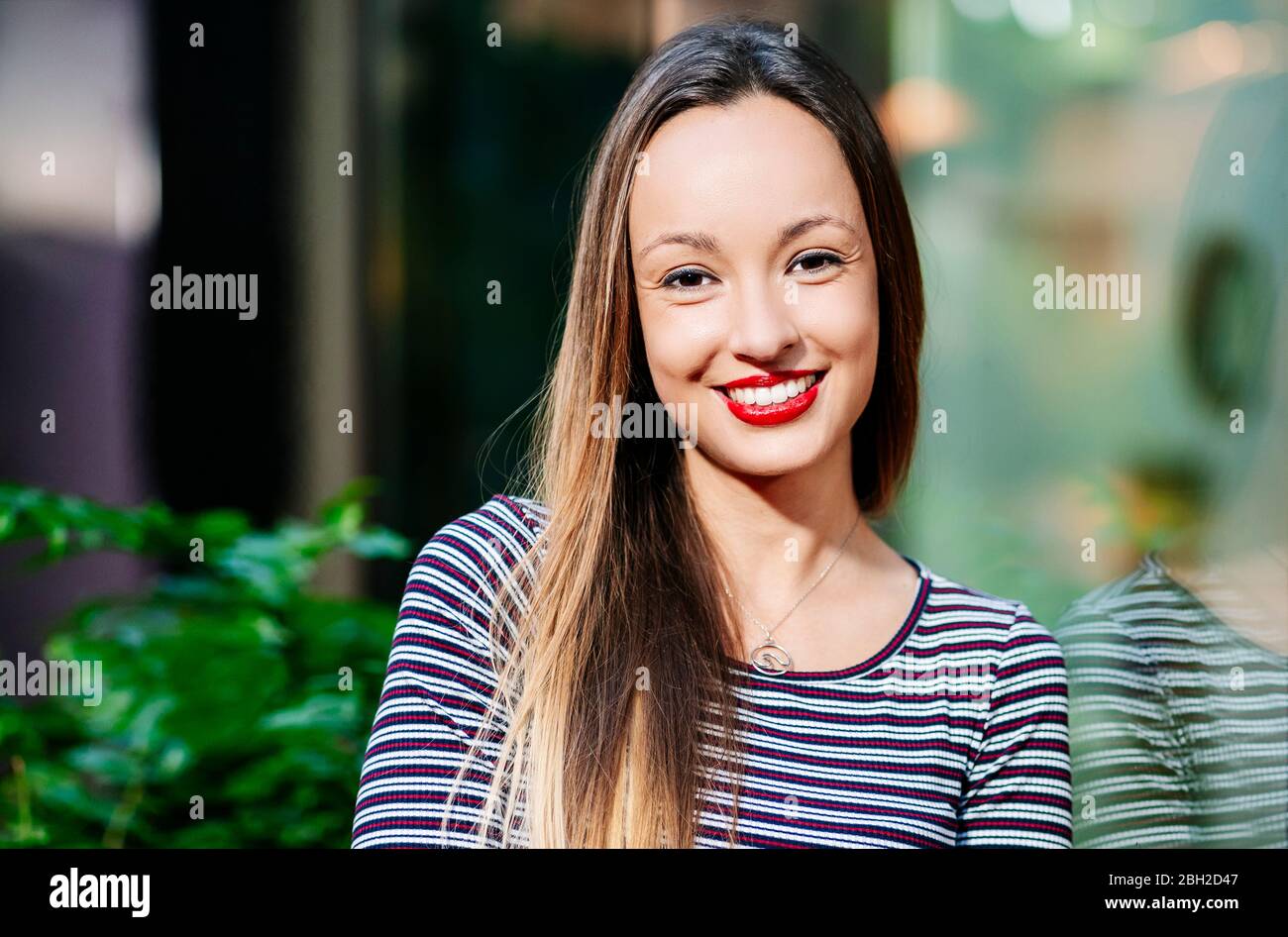 Porträt einer hübschen Frau, die sich an einer Glaswand lehnt Stockfoto