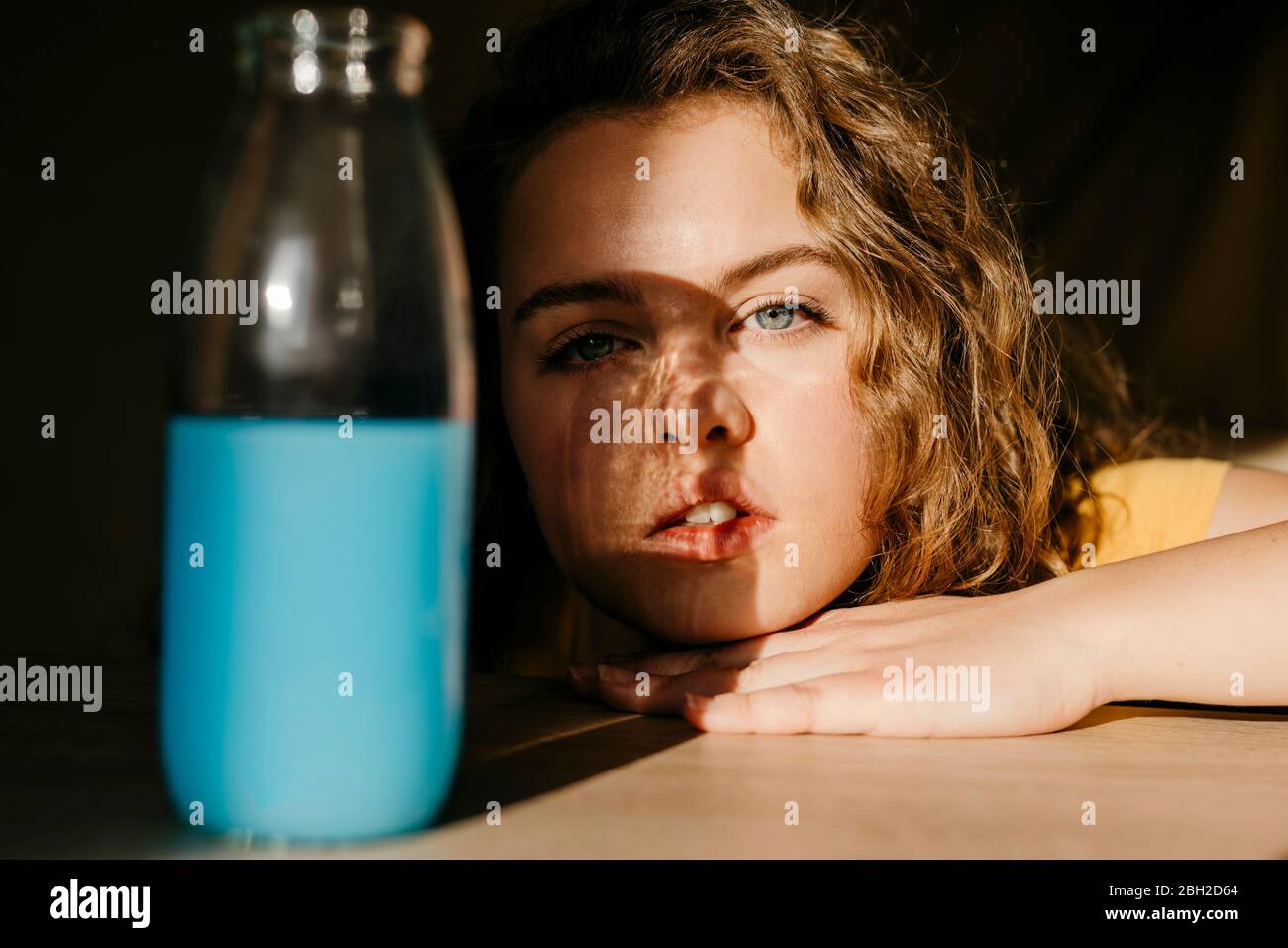 Portrait der blonden jungen Frau zu Hause mit farbigen Flasche Stockfoto