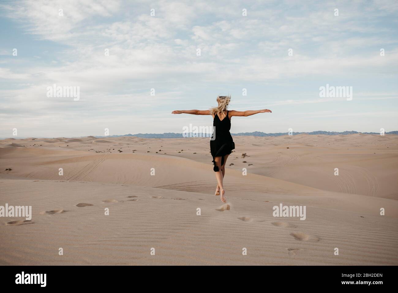 Rückansicht der blonden Frau, die in der Luft springt, Algodones Dunes, Brawley, USA Stockfoto