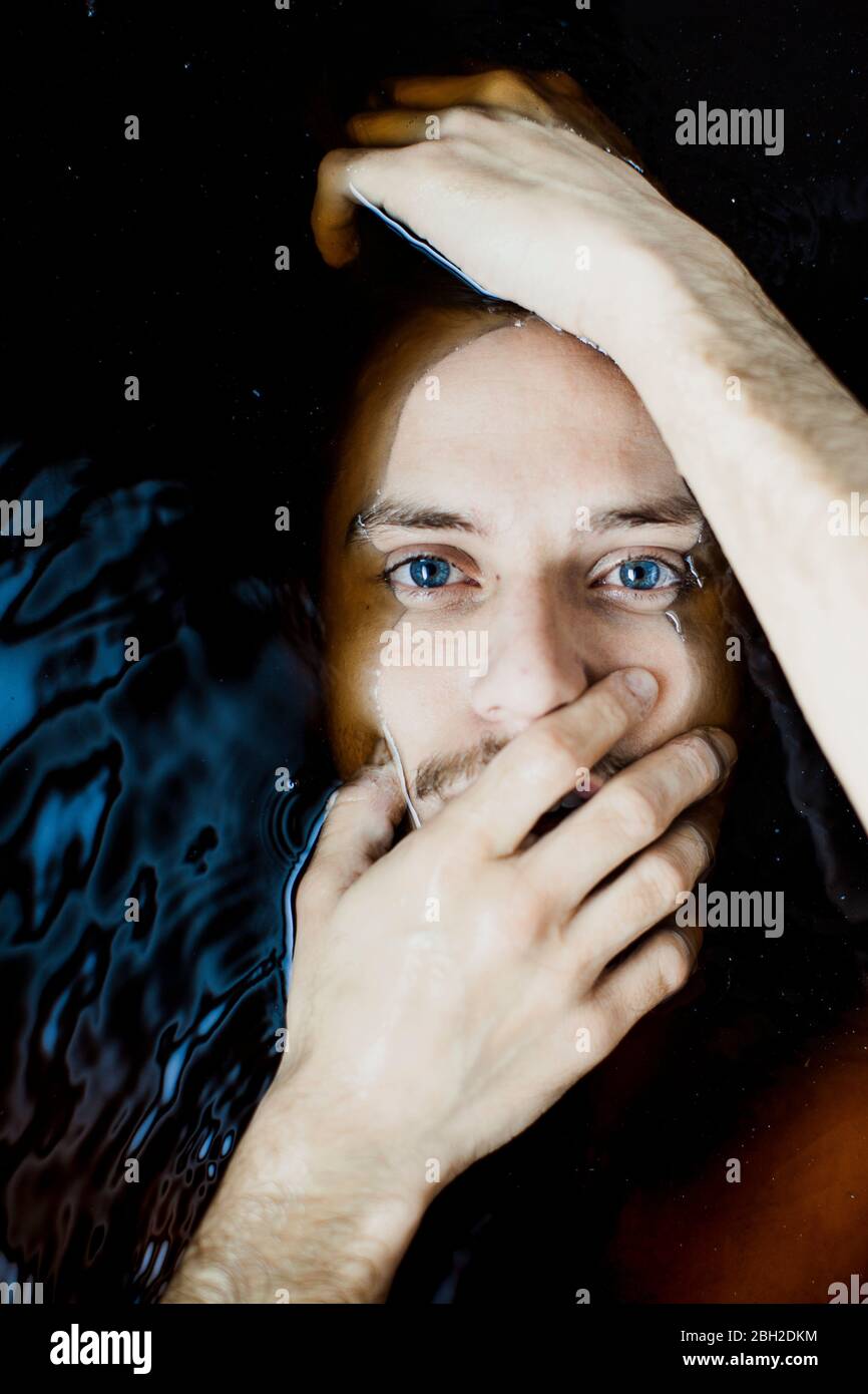 Porträt eines jungen Mannes mit blauen Augen im Wasser Stockfoto