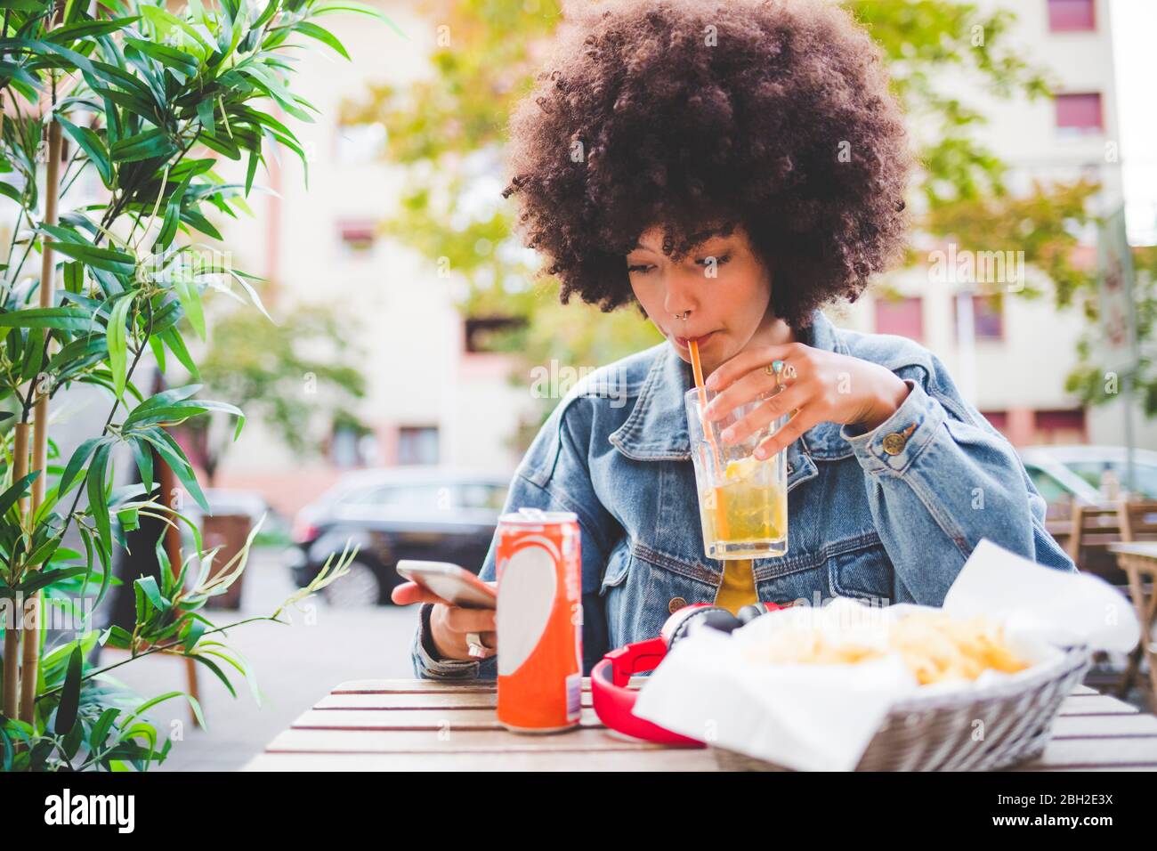 Junge Frau mit Afro-Frisur in einem Café im Freien in der Stadt Stockfoto