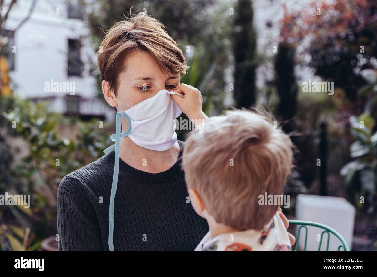 Littley Junge hilft seiner Mutter, eine Gesichtsmaske zu setzen Stockfoto