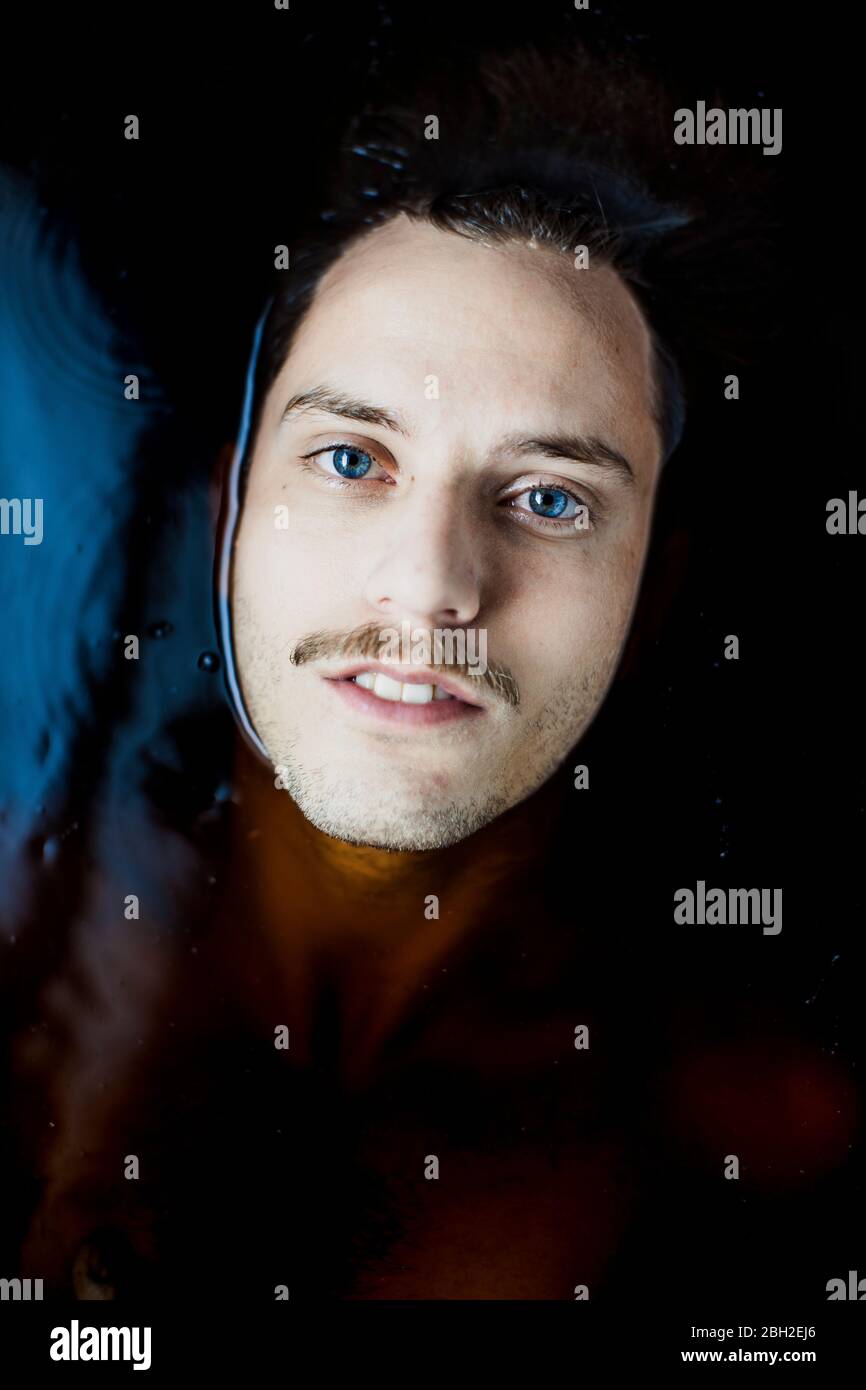 Porträt eines jungen Mannes mit blauen Augen im Wasser Stockfoto