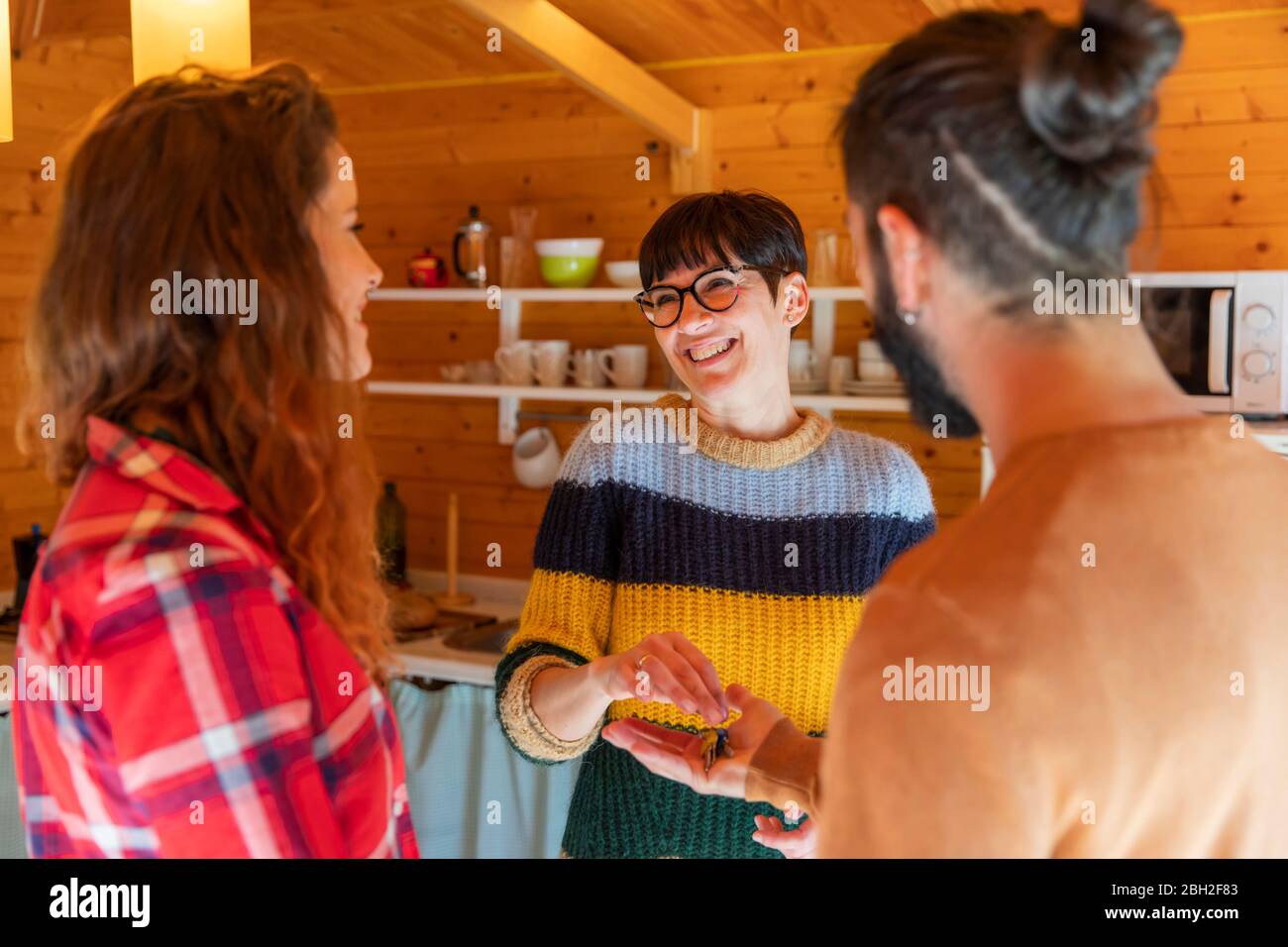 Gastgeber begrüßen junges Paar in einer Hütte auf dem Land Übergabe des Hausschlüssels Stockfoto