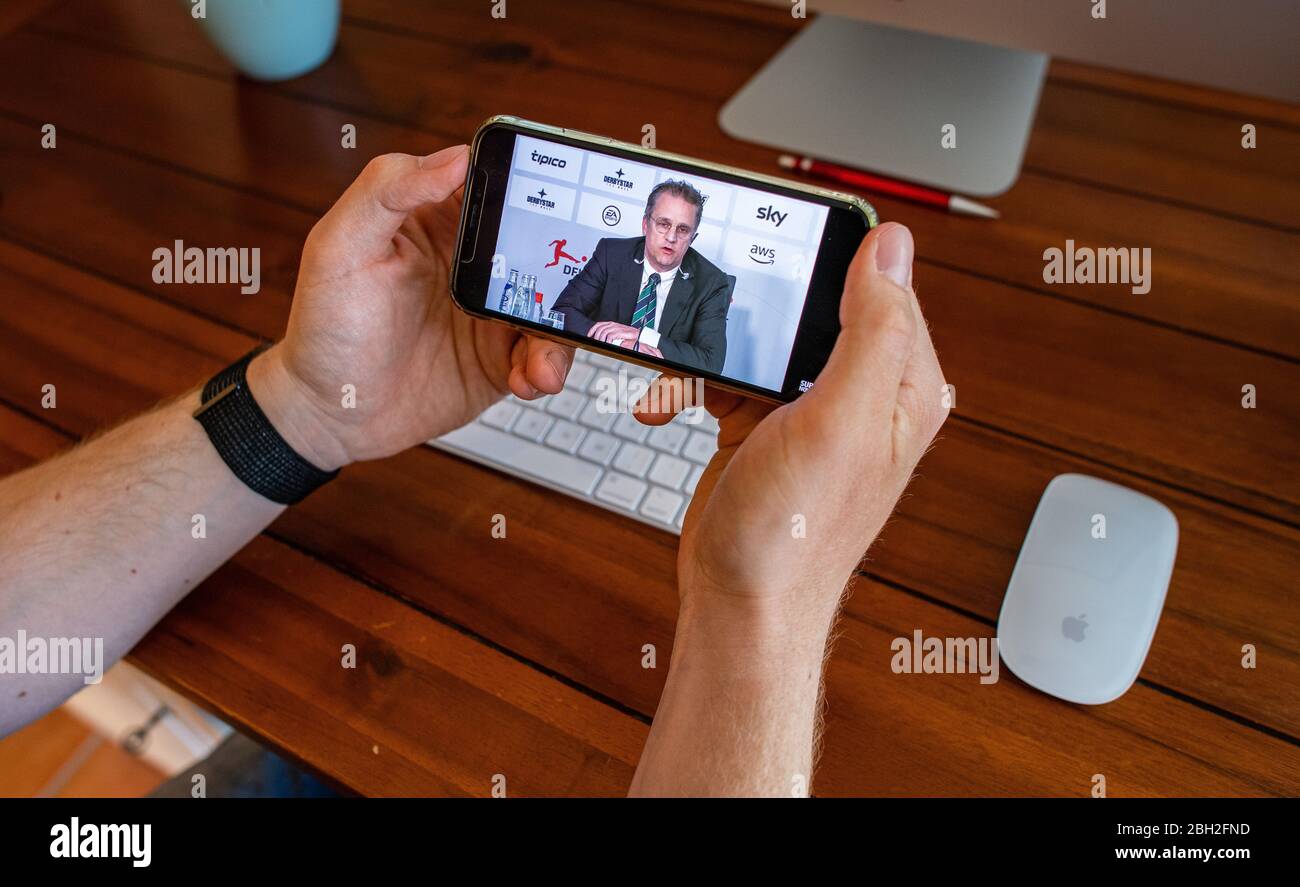 Warendorf, Deutschland. April 2020. Ein Mann schaut auf das Display seines Smartphones, Dies zeigt Tim Meyer, Chief Medical Officer des Deutschen Fußballverbandes (DFB) und Leiter der Task Force Sportmedizin/Special Game Operations der Deutschen Fußball-Liga (DFL), während einer Live-Video-Pressekonferenz nach der DFL-Mitgliederversammlung zu den Folgen der Corona-Pandemie. Kredit: Guido Kirchner/dpa/Alamy Live News Stockfoto