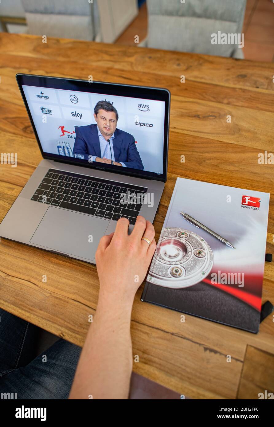 Warendorf, Deutschland. April 2020. Ein Mann schaut auf den Monitor seines Laptops, auf dem Christian Seifert, CEO und Sprecher des Vorstands der Deutschen Fußball-Liga (DFL), im Anschluss an die DFL-Hauptversammlung bei einer Live-Video-Pressekonferenz zu den Folgen der Corona-Pandemie zu sehen ist. Kredit: Guido Kirchner/dpa/Alamy Live News Stockfoto